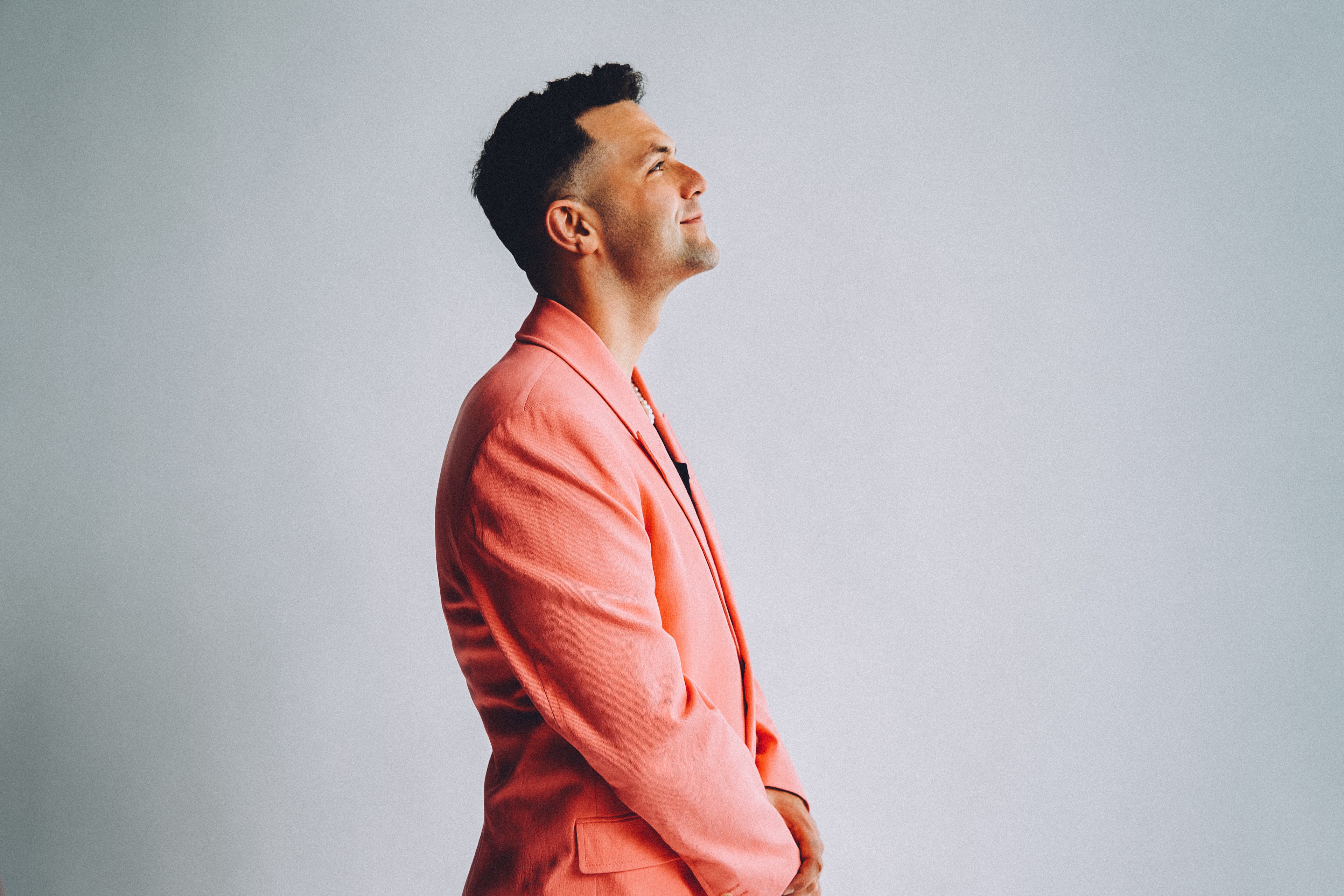 Jeremie Legault in a Pink Suit Jacket and Pearls: A Profile Portrait of Hope, Smiling Toward the Horizon with a Skin Fade Haircut